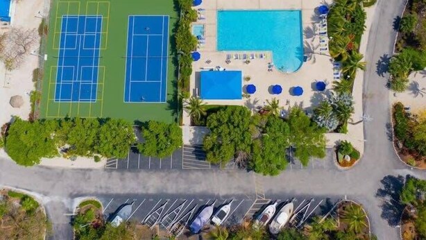 An aerial view of a resort with tennis courts, a swimming pool, and a parking area. - Marina to Ocean View Key Largo Ocean Pointe 5308 (Tavernier)