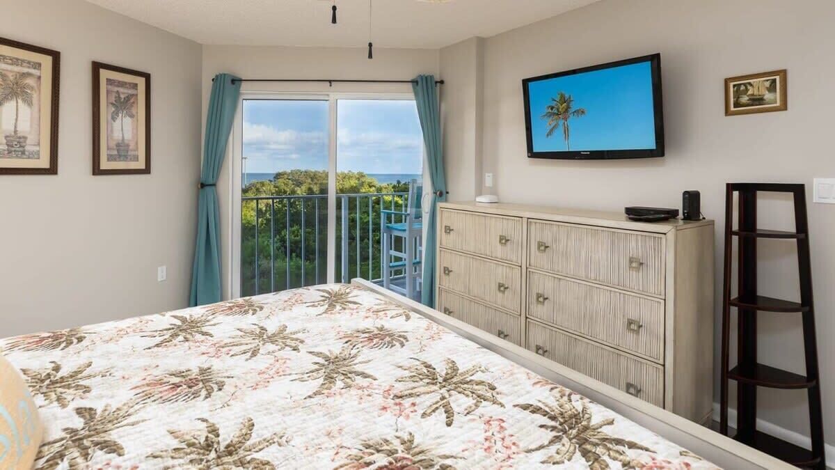 A bedroom with a bed, a wardrobe, a television, and a balcony with a view.