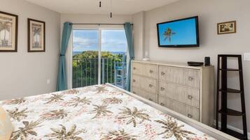 A bedroom with a bed, a wardrobe, a television, and a balcony with a view.