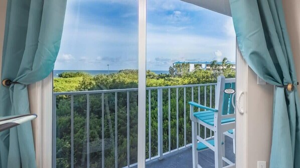 A balcony with a view of a lush green landscape and a building in the distance.