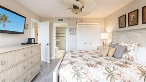 A bedroom with a bed, a television, a wardrobe, and a ceiling fan.