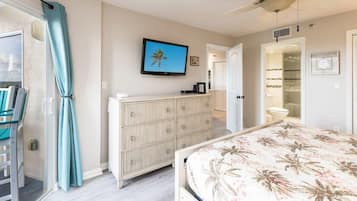 A bedroom with a bed, a TV, a wardrobe, and a bathroom visible through an open door.