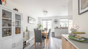 A modern kitchen with a dining area, white cabinetry, and a chandelier. - Stylish 3-Bed House in Langley|Drive - By Tempstay (Berkshire)