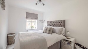 A bedroom with a bed, bedside table, lamp, and a view of the outside. - Stylish 3-Bed House in Langley|Drive - By Tempstay (Berkshire)