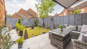 A covered patio area with outdoor furniture, a small garden, and a view of neighboring houses. - Stylish 3-Bed House in Langley|Drive - By Tempstay (Berkshire)