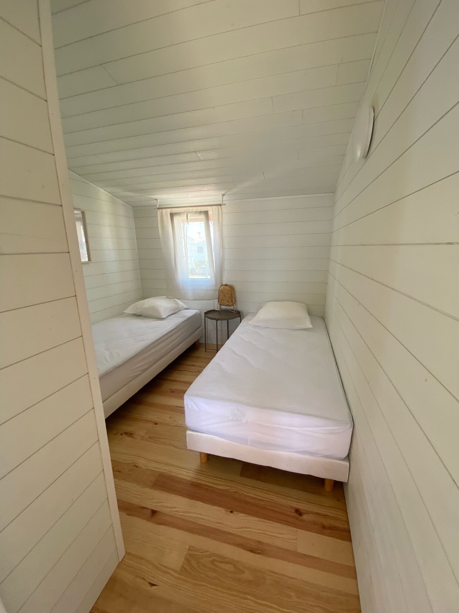Un pequeño cabañón con una cama doble, una mesita y una ventana.