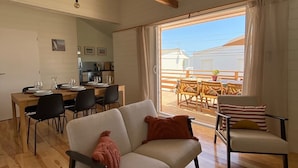 Un espacio habitable amplio con techo de madera, un sofá, una mesa de comedor con sillas y vistas al exterior.