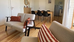 Una sala de estar acogedora con sofá, sillones y un comedor con mesa y sillas.