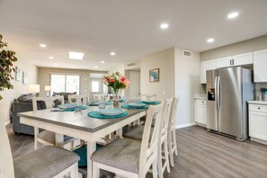 A modern kitchen with white cabinets, a stainless steel refrigerator, and a dining area with a wooden table and chairs. - Golfer's Oasis! 55+ Sun City West Retreat w/ Pool (Sun City West)