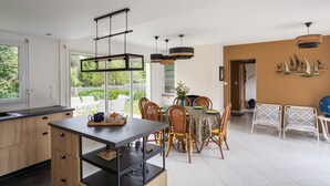A modern kitchen with a dining area, featuring a large window, wooden cabinets, and a central island.