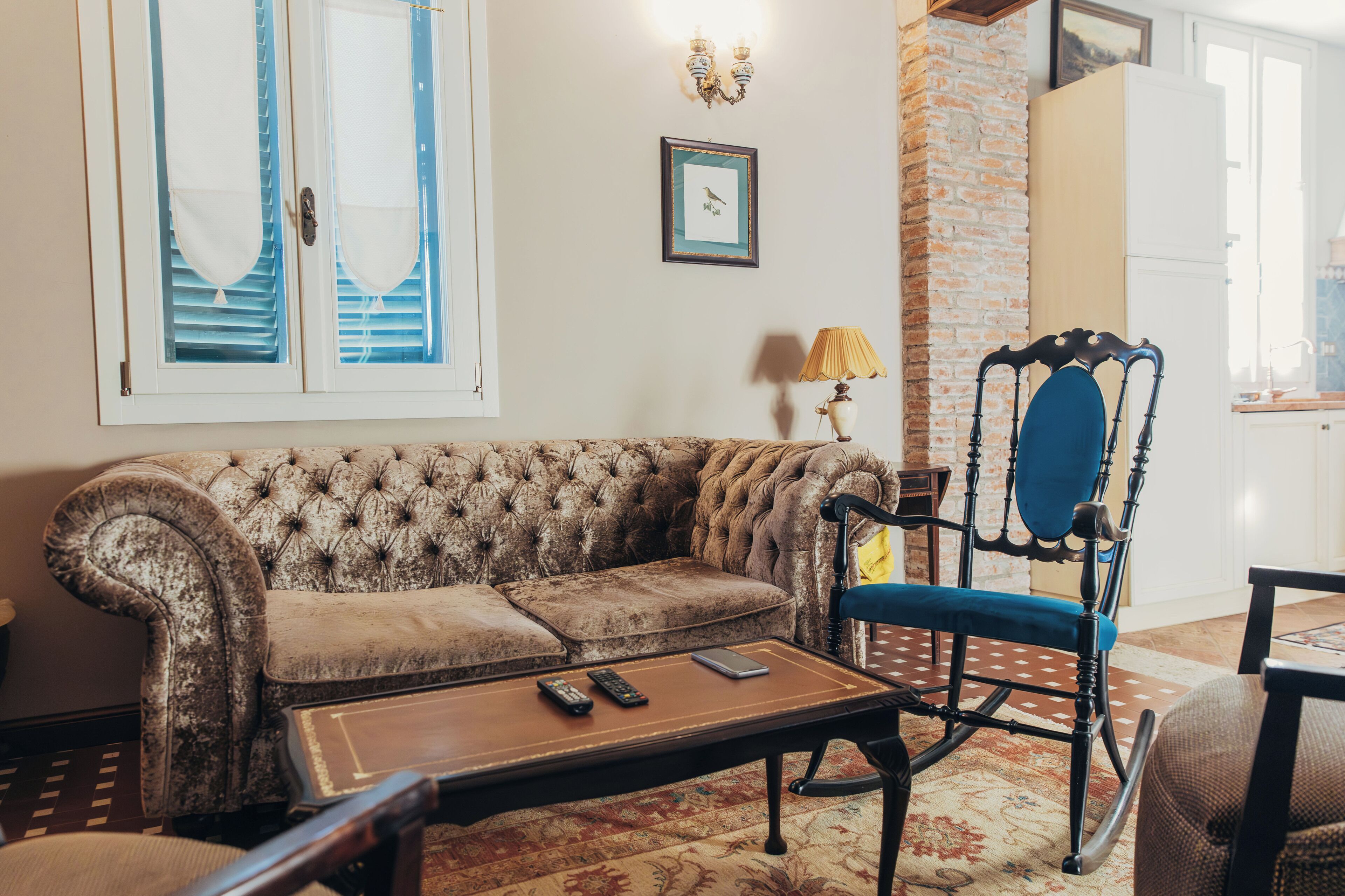 A living room with a tufted sofa, a rocking chair, a coffee table, and a patterned rug.