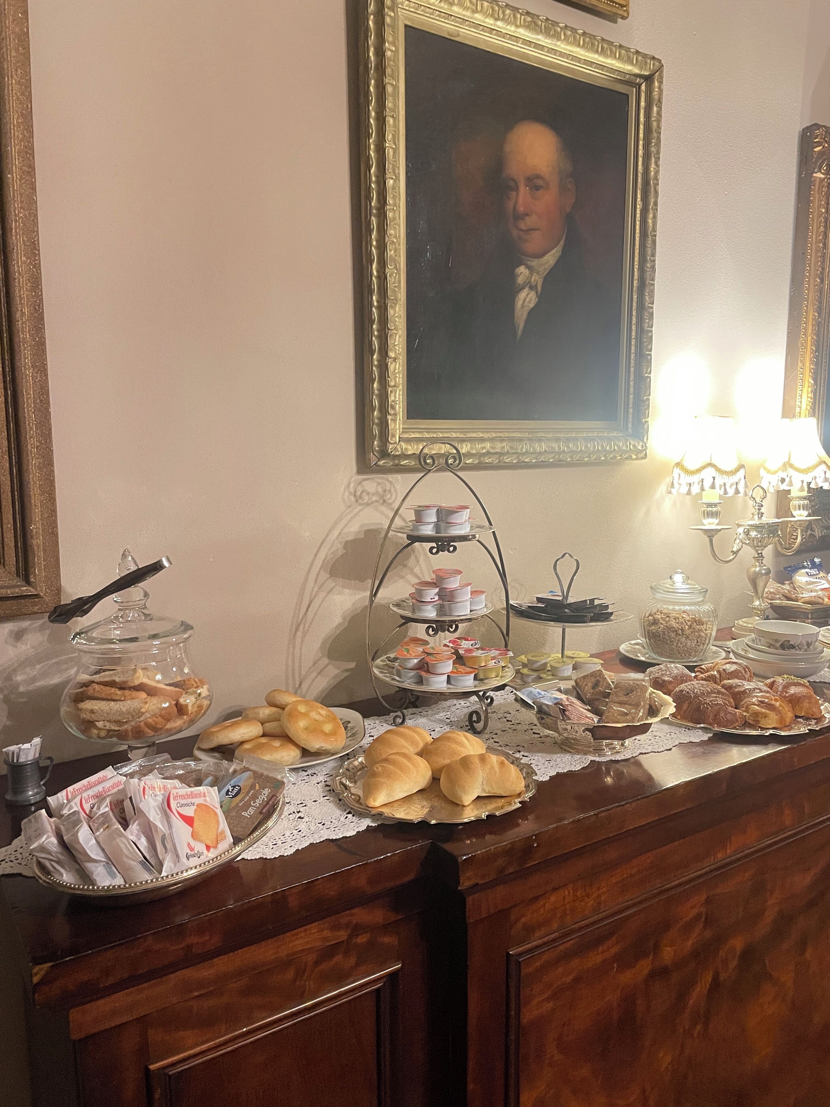 Una mesa de bufé con diversos alimentos y un retrato enmarcado en la pared.