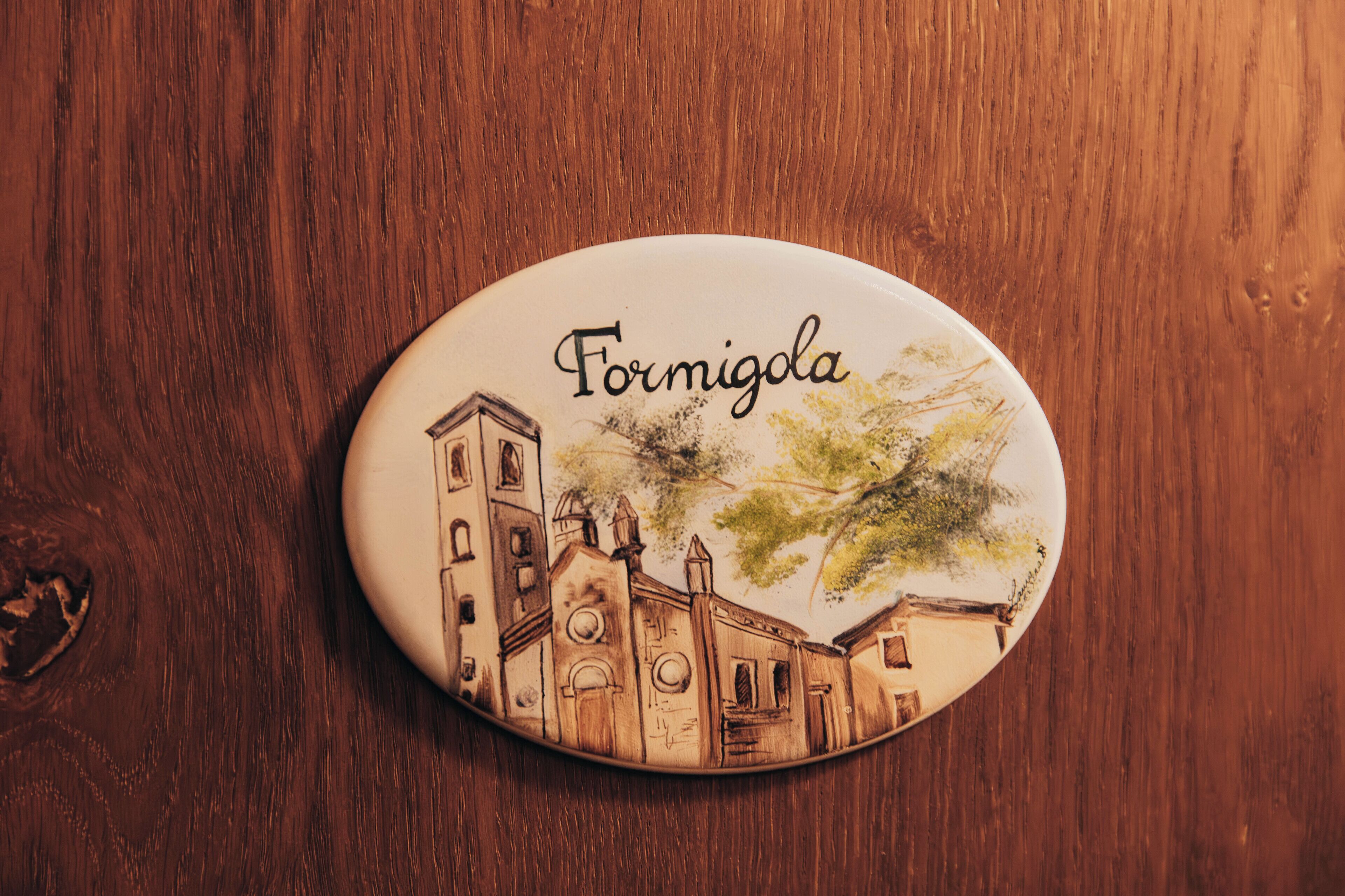 Une assiette décorative ornée d’un dessin représentant une ville, sur laquelle on peut lire le nom « Formigola ».
