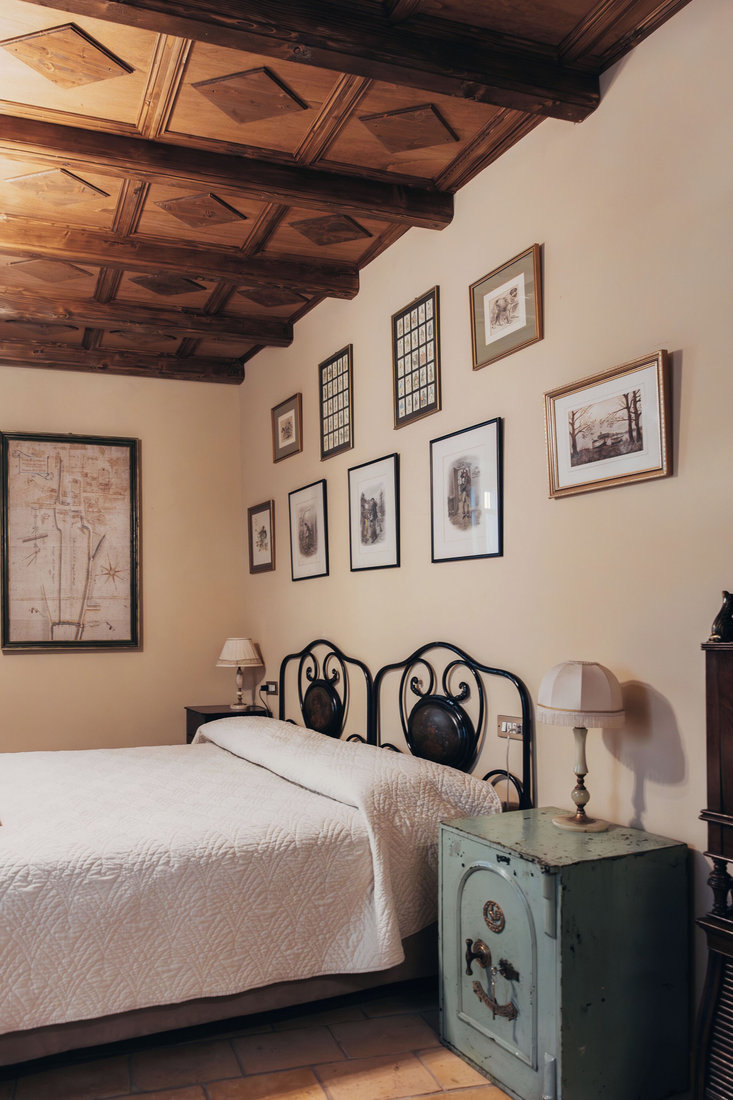 Ein Schlafzimmer mit einem Bett, einem Nachttisch, einer Lampe, einer Kommode und gerahmten Bildern an der Wand.