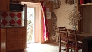 Una cocina rústica con armarios de madera, una pared de piedra y un comedor con mesa y sillas de madera.