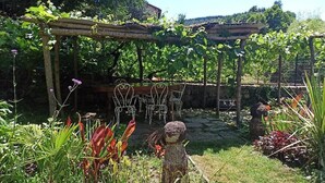 Un jardín con una pérgola, sillas y una estatua.