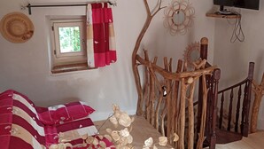 Una habitación rústica con techo de madera, un televisor montado en la pared, una ventana con cortina y una valla decorativa de madera.