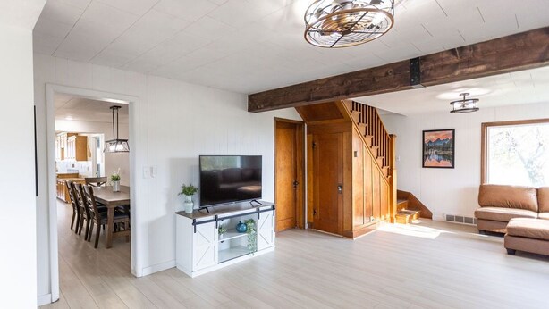 Un salón amplio con una escalera de madera, un televisor y un sofá.