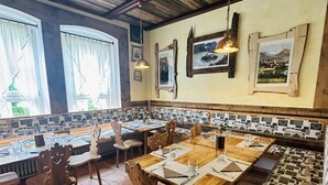 Un restaurante con mobiliario de madera, piso de baldosas y obras de arte en las paredes.