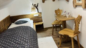 Un dormitorio con una cama, un escritorio de madera, una silla y dos marcos de cuadros en la pared.