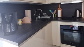 A modern kitchen with white cabinets, a Bosch coffee maker, a kettle, and a toaster.