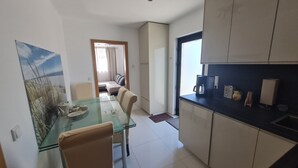 A modern kitchen with white cabinets, a glass dining table, and a view of the dining area.