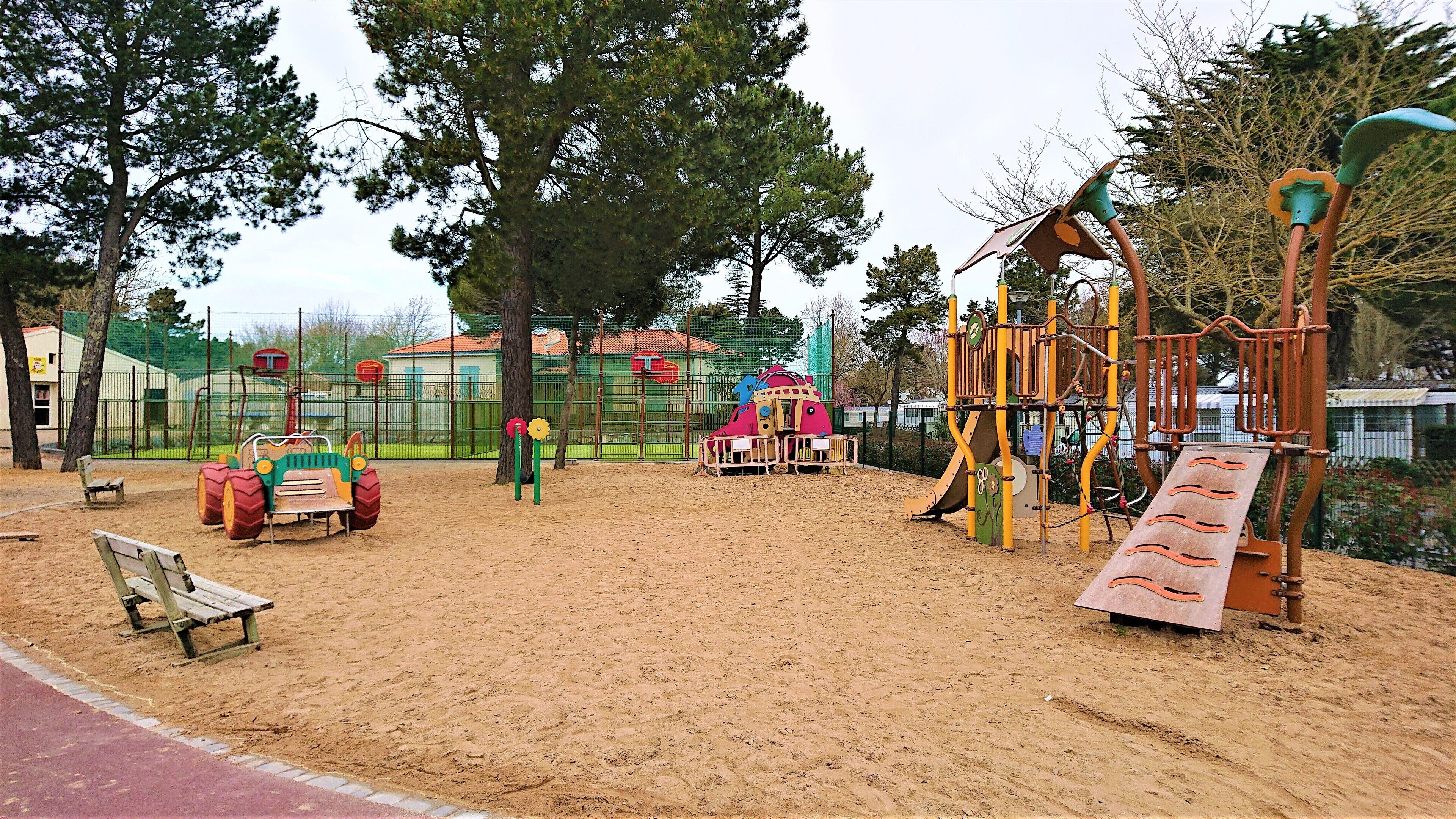 A playground with sand, a bench, and a climbing structure.