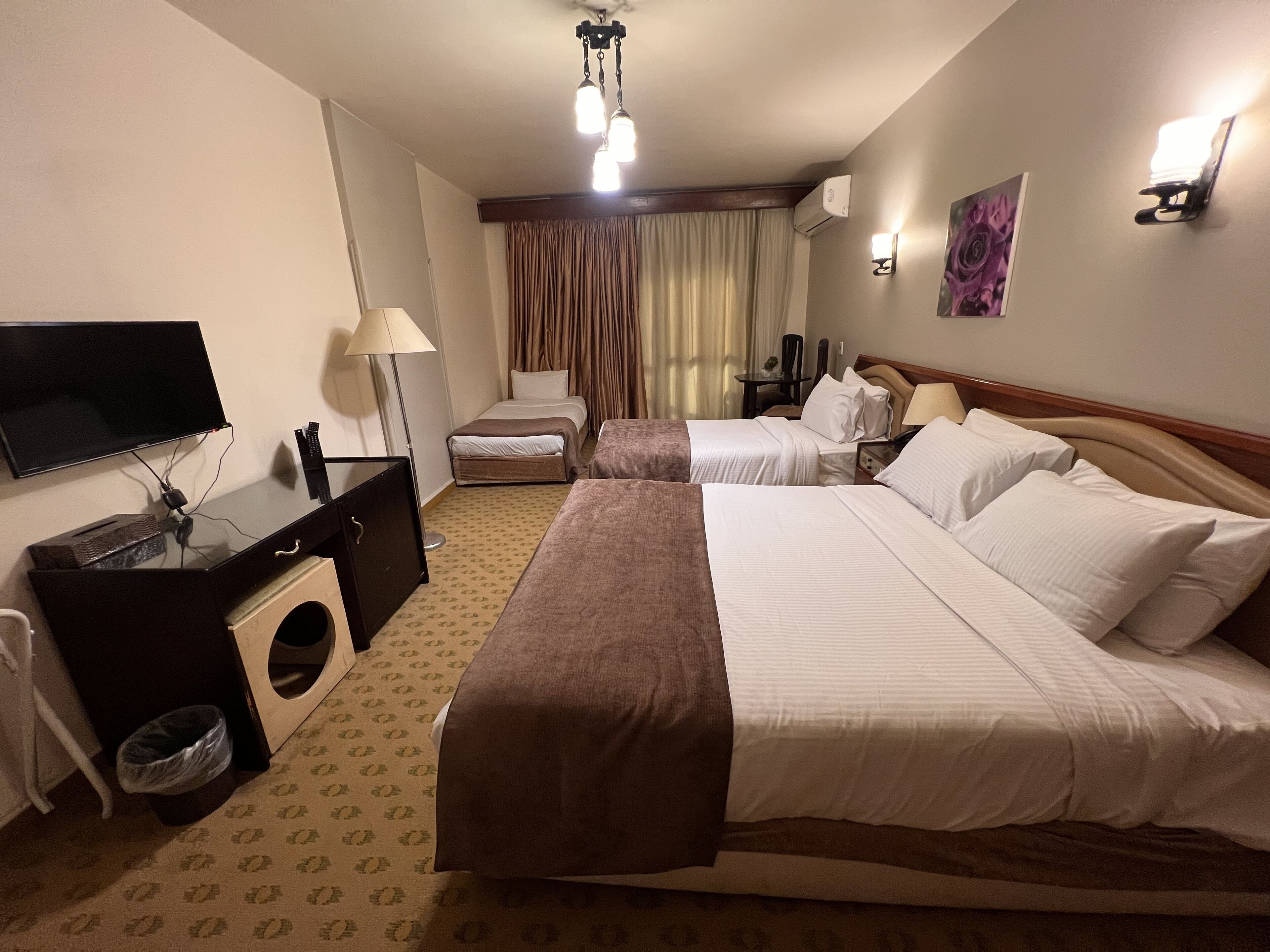 Una camera d'albergo con due letti, una scrivania con un computer, una televisione e un bagno.