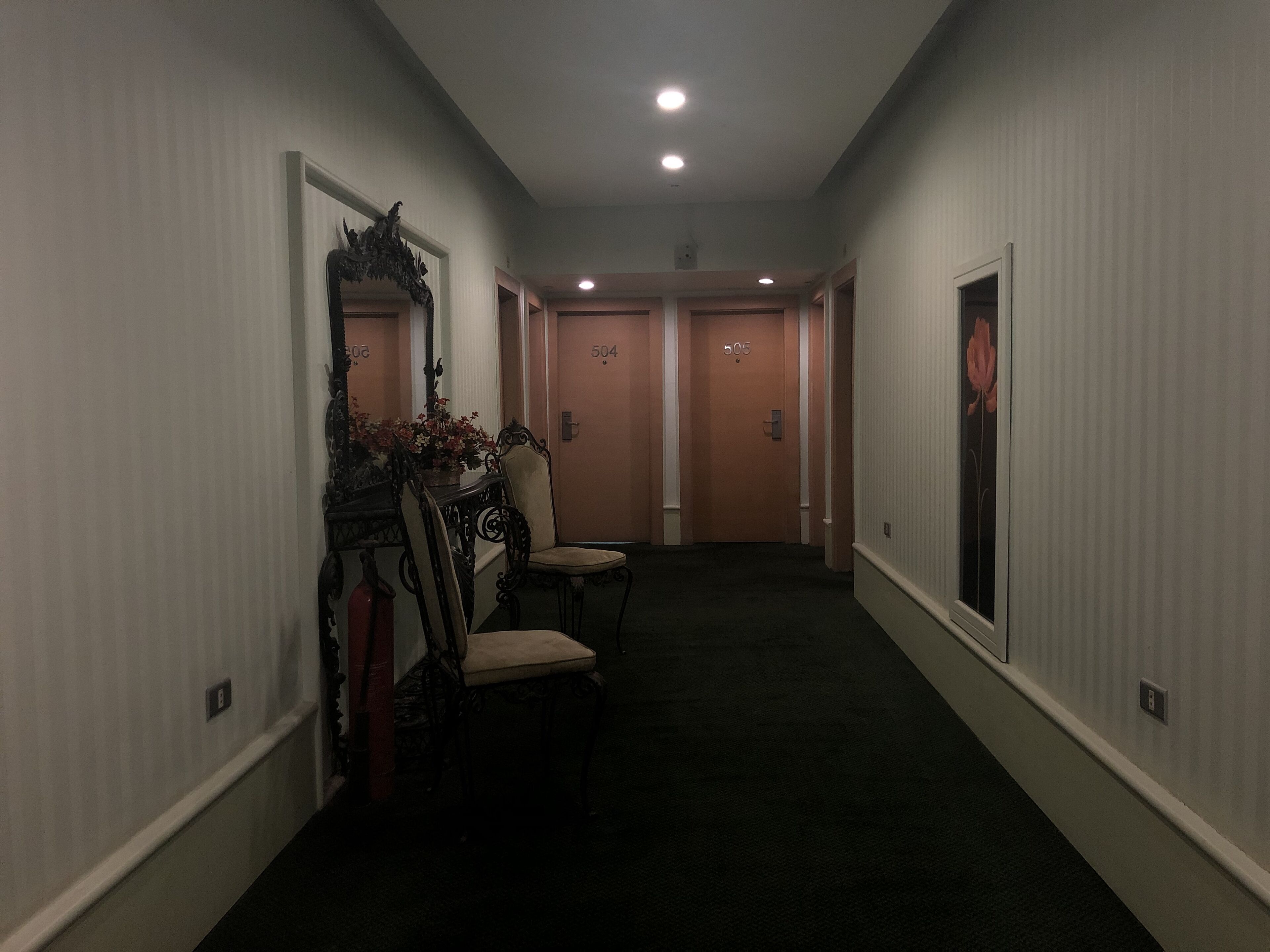 A hallway with a chair, a mirror, and a door with the number 504.