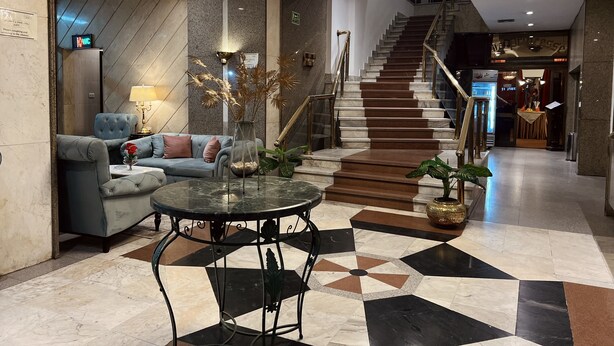 Um hall com uma escadaria imponente, um sofá confortável, uma mesa redonda e um candelabro.