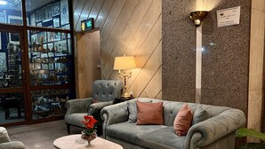 Um hall com um sofá cinzento, poltronas, uma mesinha com um vaso e um abajur.