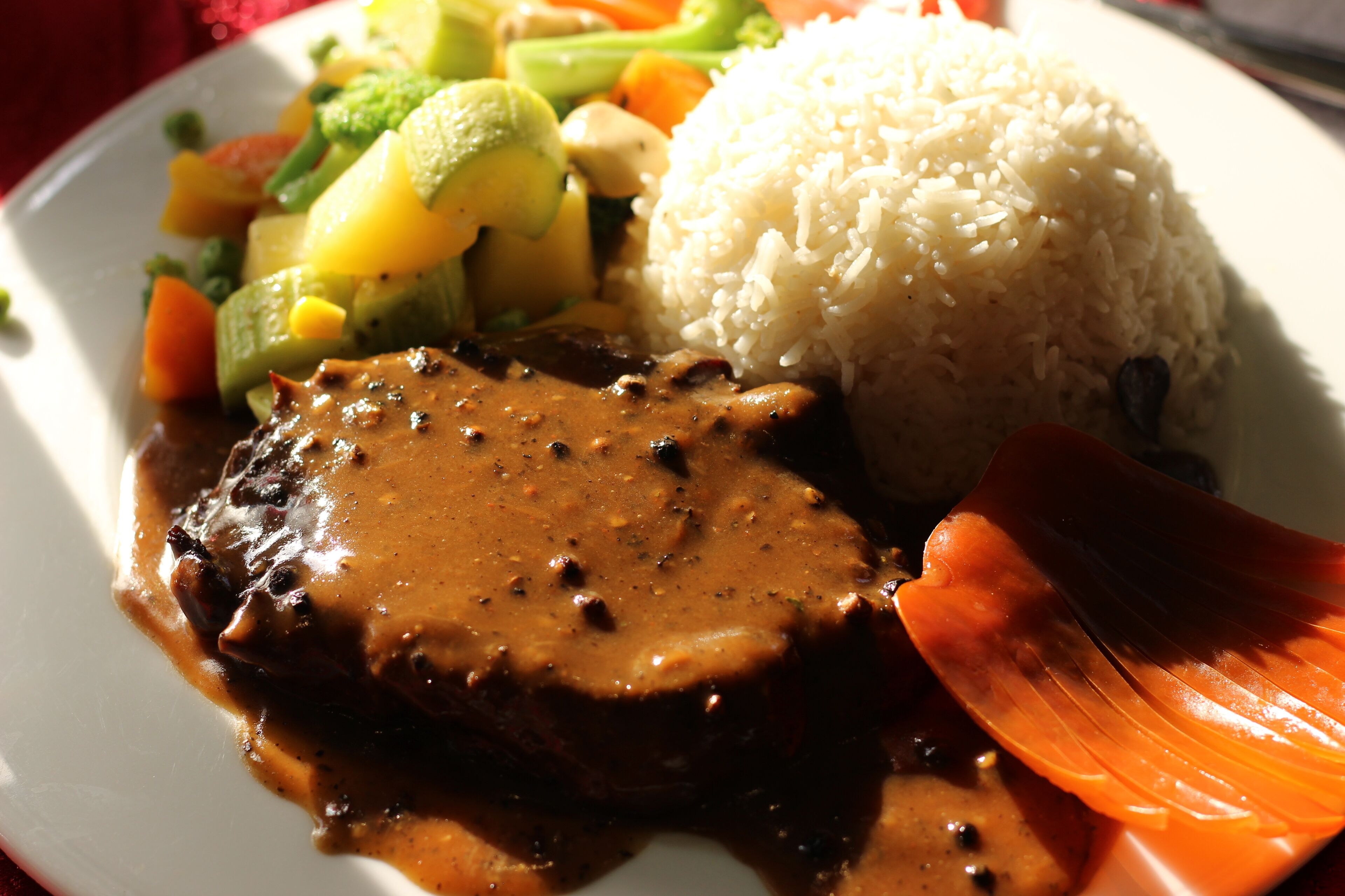 Une assiette contenant un morceau de viande, du riz et des légumes.