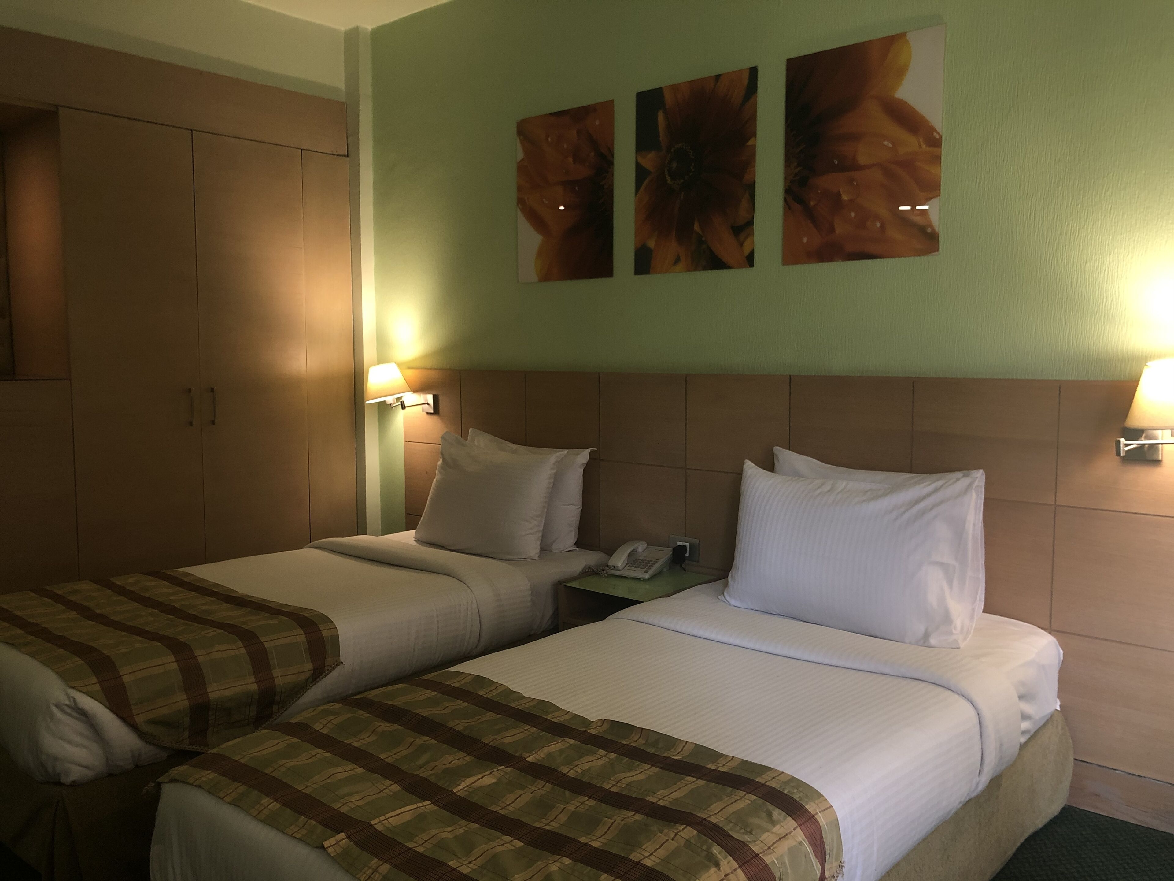 Habitación de hotel con dos camas, una mesita de noche, un teléfono y lámparas fijadas a la pared.