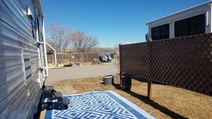 Un jardin avec un tapis à motifs bleus, un patio couvert et un espace clos délimité par une clôture.