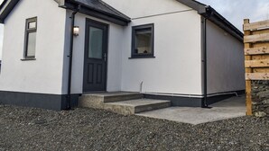A modern two-story building with a dark-colored front door, a small window, and a visible staircase leading to the entrance. - 2 bedroom accommodation in Llanfachraeth, near Holyhead (Llanfachraeth, near Holyhead)