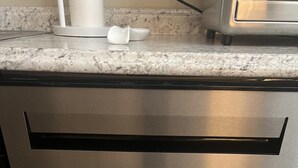 Lavastoviglie in acciaio inox in una cucina con piano di lavoro in granito.