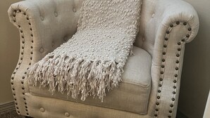 Una poltrona trapuntata con una coperta a frange.
