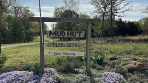 Et træskilt med teksten "Mud Hut" og "7125s 1875 RD" som viser en placering.