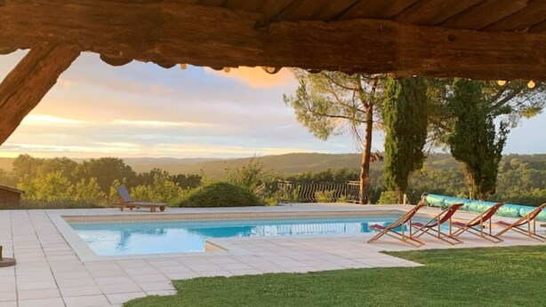 Un espace piscine avec vue sur les collines, un patio couvert et une pelouse.