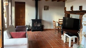 Un salon chaleureux avec une cheminée, un canapé, un téléviseur et un coin repas.