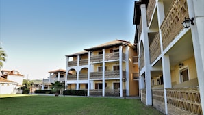 A multi-story building with balconies, a courtyard, and a well-maintained lawn. - Elpida Hotel (Zakynthos)