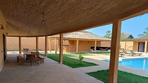Un espacio al aire libre cubierto con piscina, mobiliario y bar.
