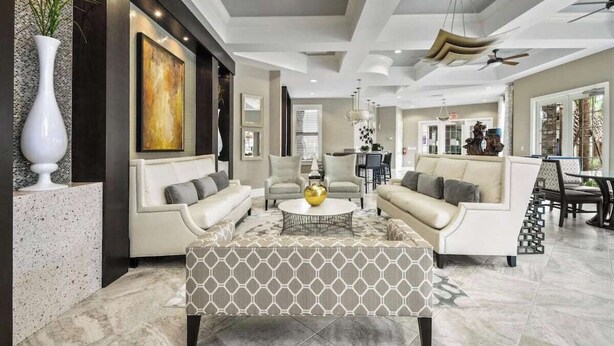 Un amplio salón con diseño moderno, que incluye un gran sofá, una mesa de centro y un jarrón decorativo.