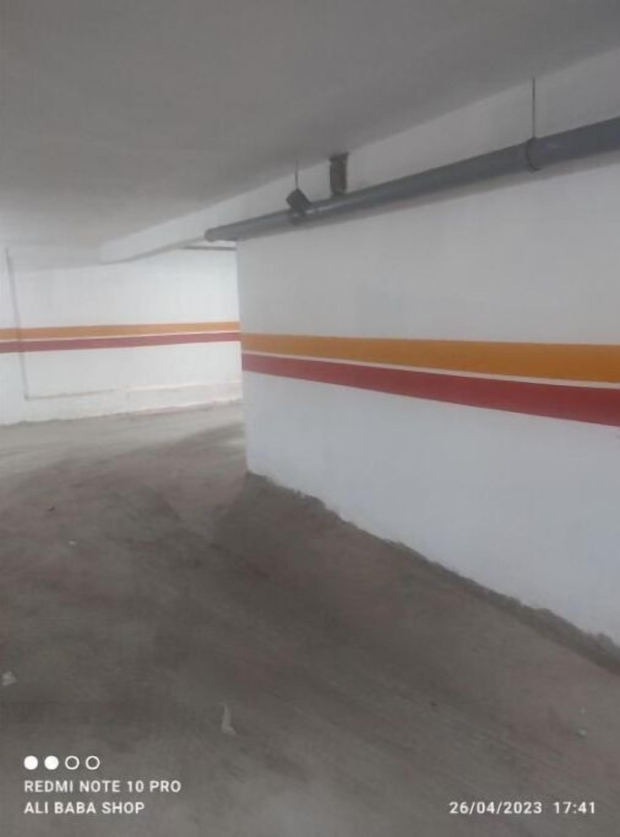 Tyhjä pysäköintihalli, jonka seinät ovat valkoiset ja jossa on oransseja raitoja.