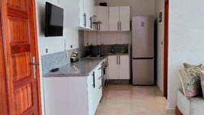 A compact kitchen with white cabinets, a built-in oven, and a refrigerator.