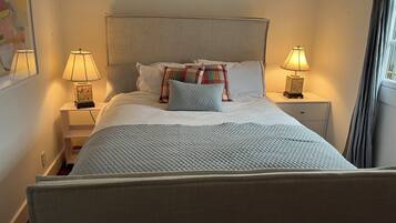A neatly made bed with a quilted blanket, two bedside lamps, and a nightstand with a lamp.
