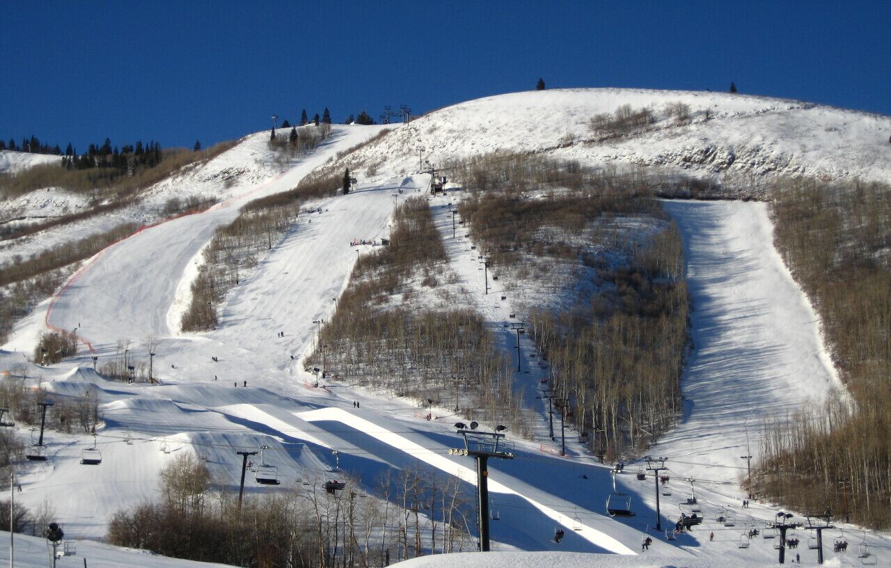 A ski slope with ski lifts, trees, and a clear sky.
