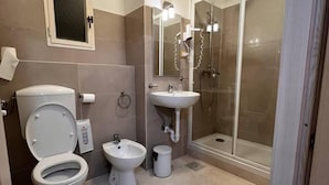 A modern bathroom with a toilet, bidet, sink, and glass-enclosed shower. - Shelter Affittacamere (Genoa)