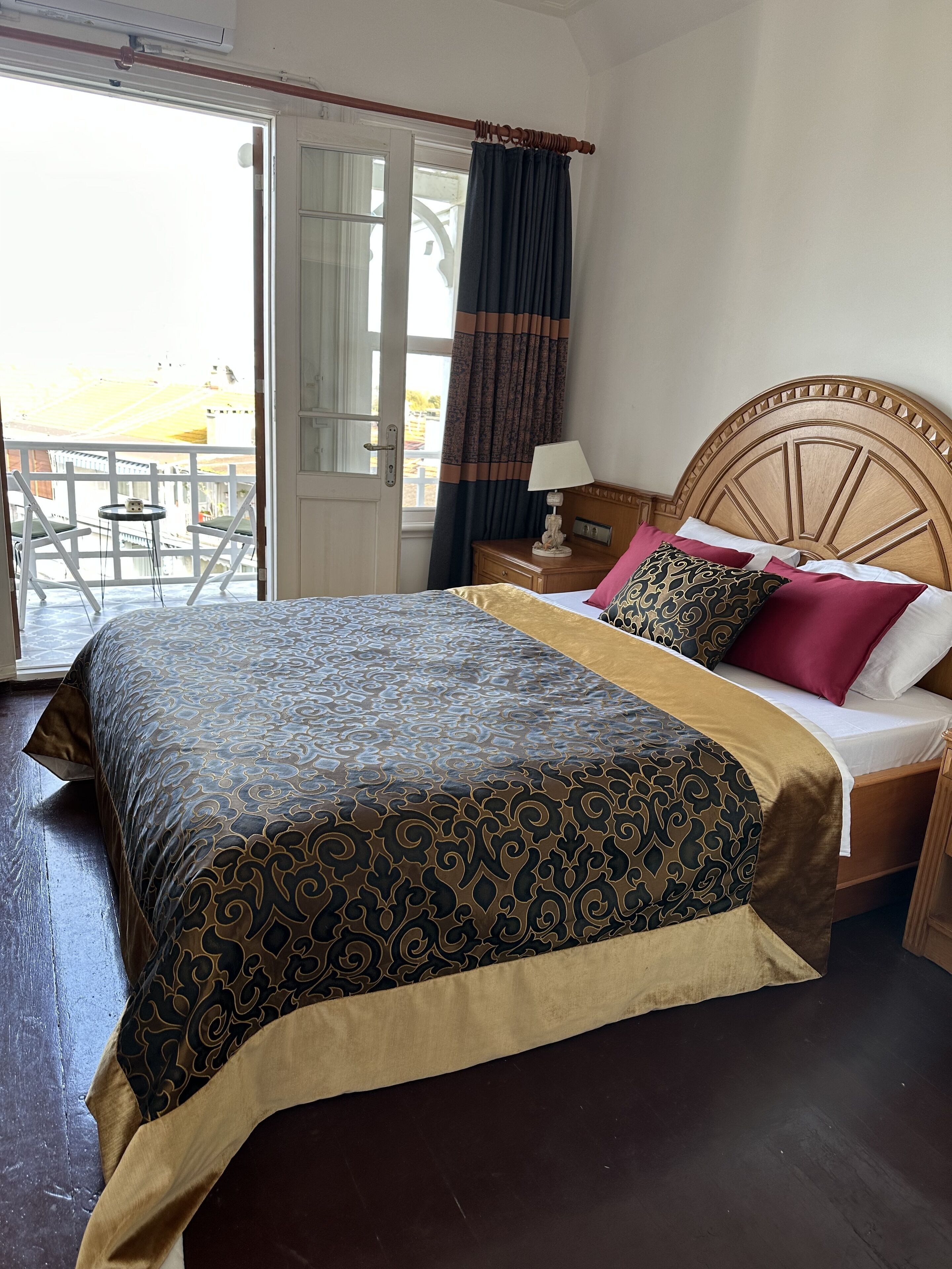 Et hotelværelse med en seng, et natbord, en lampe og udsigt ud.