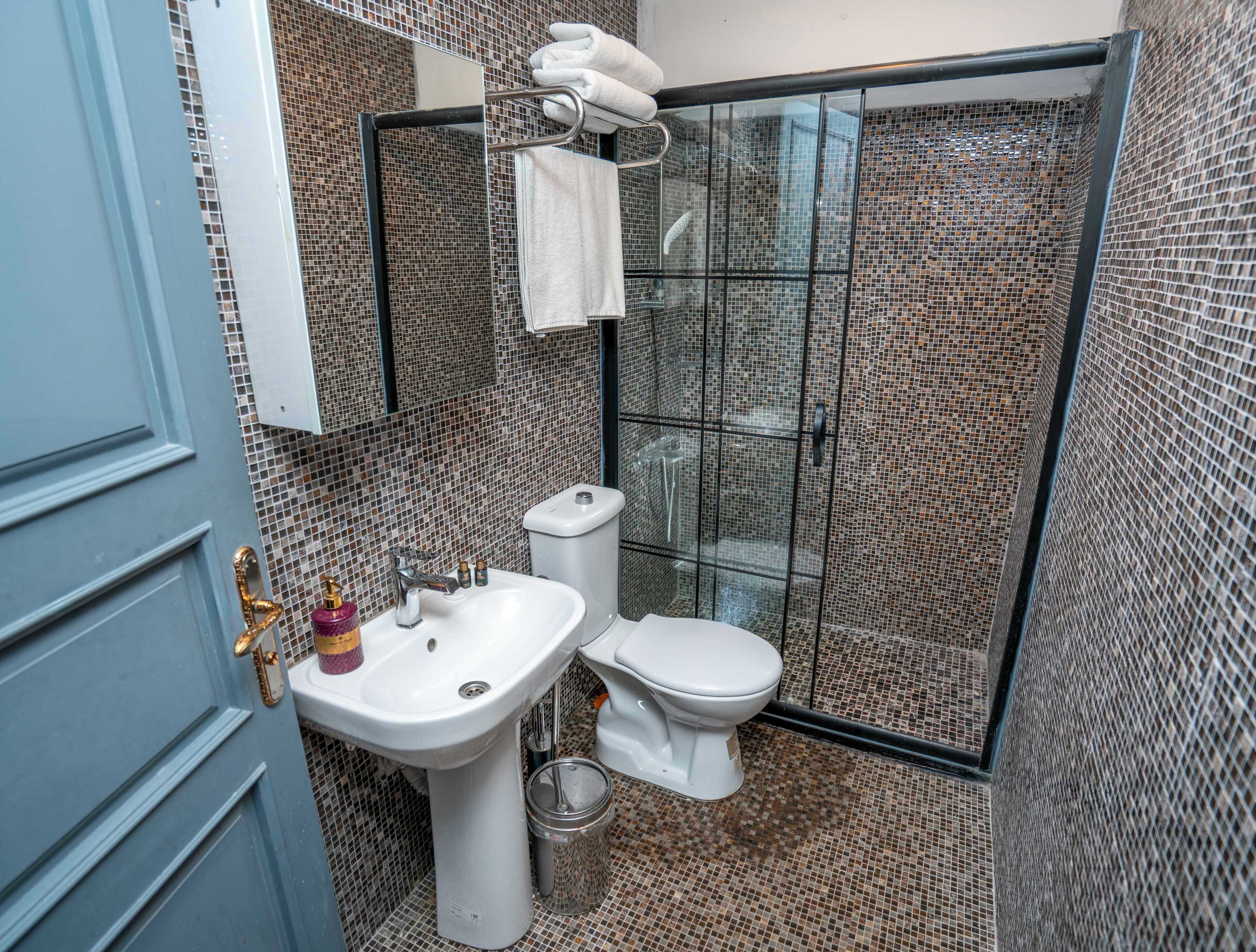 Un bagno con box doccia piastrellato, lavandino e WC.